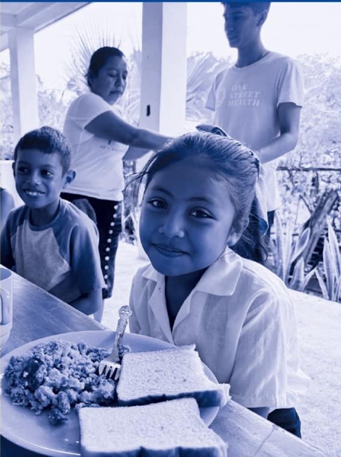 A girl smiling at the table while eating breakfast at a CCCG feeding program